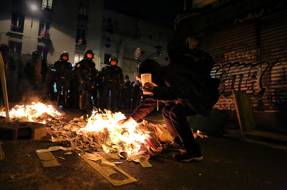 Policiais em frente a manifestante em protestos na noite da eleição presidencial em Menilmontant, distrito de Paris  (Foto: Lara Priolet / AFP)