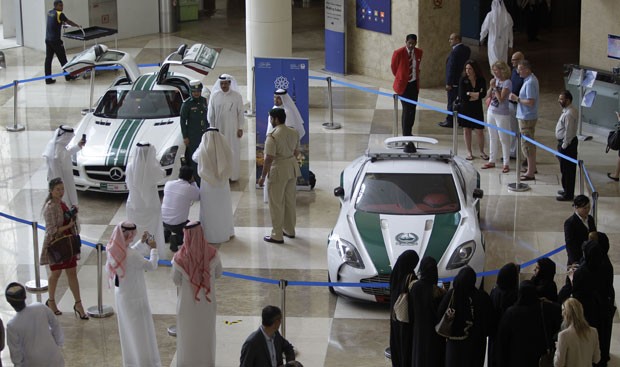 Visitantes fotografam  Aston Martin One-77, à direita, e Mercedes SLS, que são usados pela polícia de Dubai (Foto: Kamran Jebreili/AP)