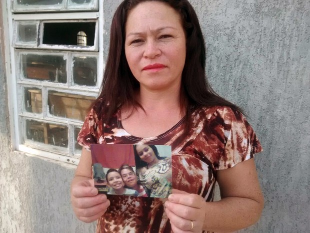Ex-usuária de drogas que morou em bueiro no Distrito Federal, Odânia Batista Garcez segura fotos dos três filhos (Foto: Isabella Calzolari/G1)