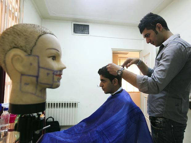 Barbeiro corta cabelo de freguês em salão oficial em Teerã nesta segunda (5). O Irã lançou um guia com modelos de corte de cabelo considerados apropriados para iranianos. (Foto: AP)
