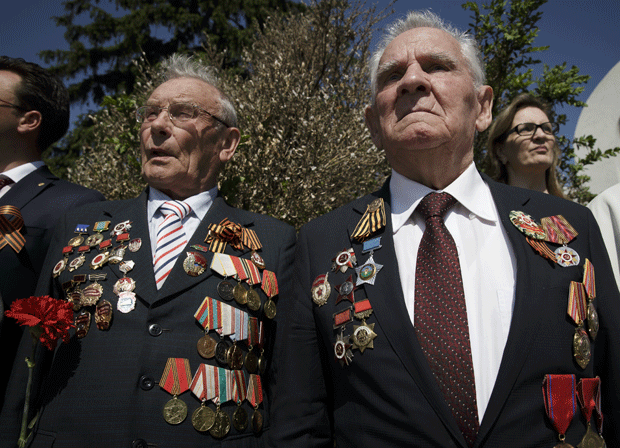 Veteranos russos com o peito coberto de medalhas participam de cerimônia no Cemitério dos Heróis Soviéticos em Bucareste nesta sexta (8) (Foto: Vadim Ghirda/AP)