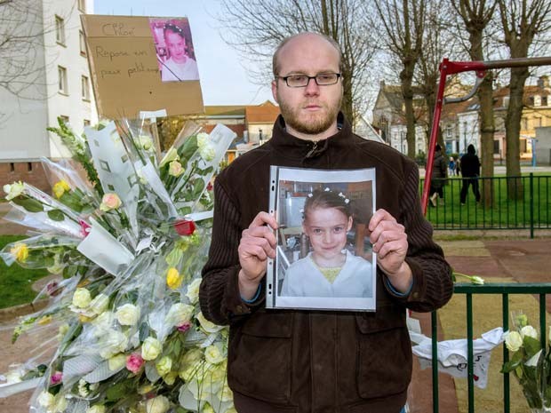 Homem segura foto de Cloé, menina de 9 anos que foi sequestrada e morta na França, diante de memorial à garota em playground de Calais (Foto: FP PHOTO / PHILIPPE HUGUEN)