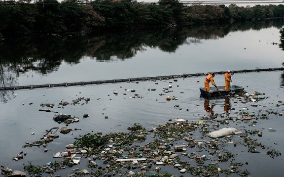 Trabalhadores retiram o lixo retido na &quot;eco-barreira&quot; na entrada da Baía de Guanabara, em Duque de Caxias, no Rio (Foto: YASUYOSHI CHIBA / AFP)