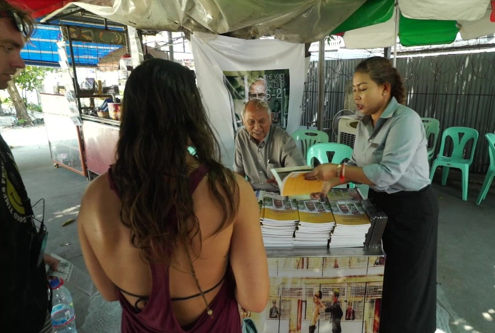 Hoje, Chum Mey dedica-se a vender o livro que escreveu sobre seu tempo na prisão (Foto: BBC)