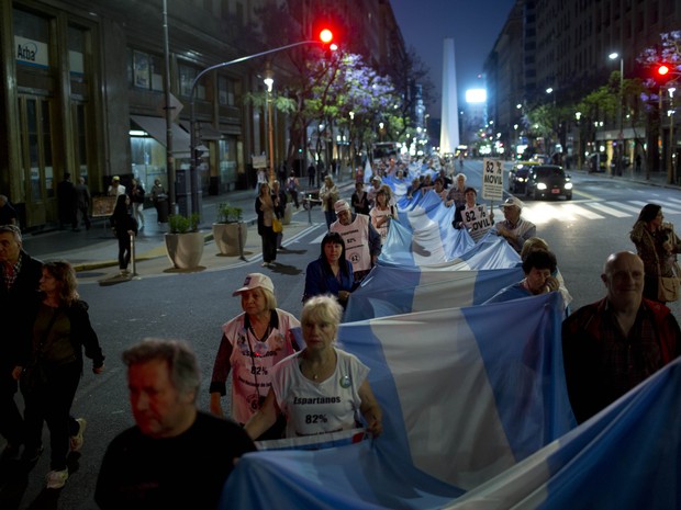 Manifestantes levam bandeira da Argentina durante caminhada em Buenos Aires (Foto: Natacha Pisarenko/AP)