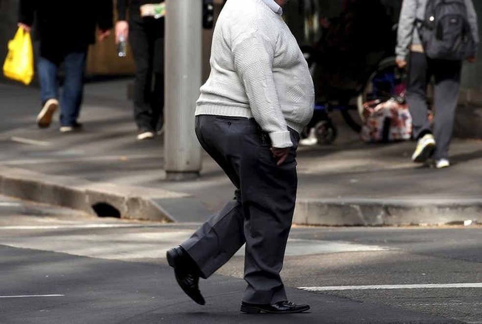 Pedestre com sobrepeso atravessa rua (Foto:  David Gray/Reuters)