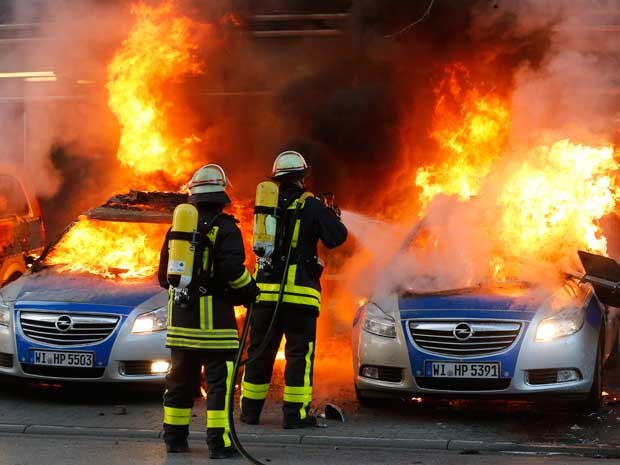 Bombeiros tentam apagar fogo em carros em Frankfurt. (Foto: Michael Probst / AP Photo)