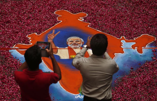 Indianos tiram fotos de imagem de Narendra Modi feita de talco colorido e envolta em pétalas de rosas, nesta sexta-feira (16) (Foto: Saurabh Das/AP) Indianos tiram fotos de imagem de Narendra Modi feita de talco colorido e envolta em pétalas de rosas, nesta sexta-feira (16) (Foto: Saurabh Das/AP)