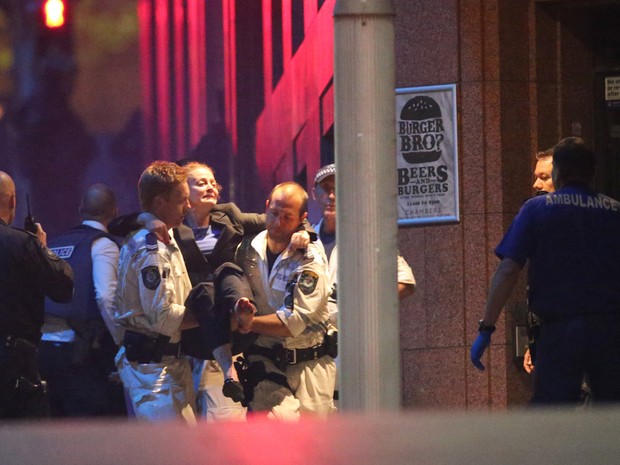 Uma refém ferida é carregada por paramédicos do lado de fora do Lind Cafe em Sydney, na Austrália (Foto: Rob Griffith/AP)