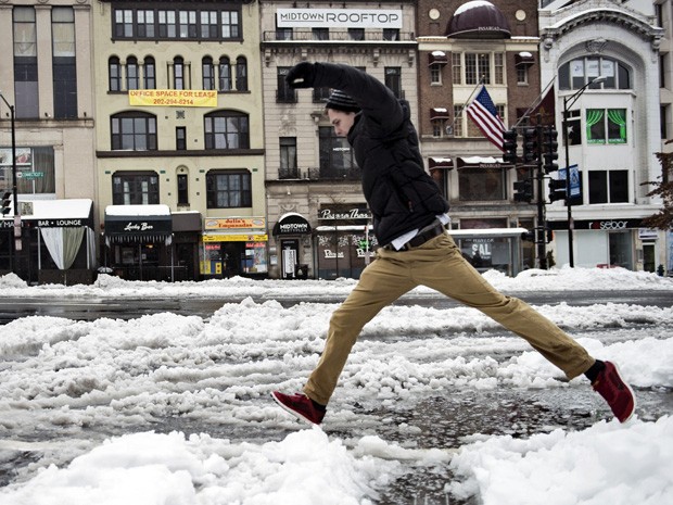 Homem pula poça em na avenida Connecticut, em Washington. O distrito de Washington teve a primeira forte tempestade de inverno nesta quinta-feira (13). (Foto: Brendan Smialowski/AFP)