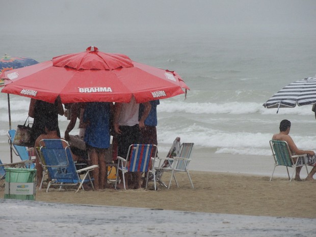 Guarda-sol funciona como guarda-chuva a turistas que não dispensam a praia nem em dias nublados (Foto: Géssica Valentini/G1)