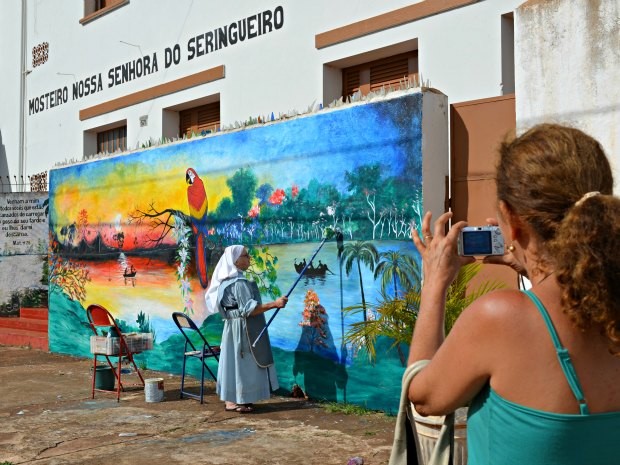 Cena da monja pintando o muro chama a atenção de quem passa na rua (Foto: Rosiane Vargas/G1)