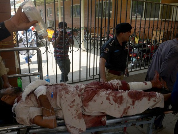 Policiais carregam vítimas ferida em ataque suicida em tribunal em Mardan, no Paquistão, nesta sexta-feira (2) (Foto: Hasham Ahmed / AFP)