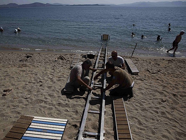 Homens trabalham na instalação do Seatrac na praia de Nea Makri, a leste de Atenas (Foto: Yorgos Karahalis/Reuters)