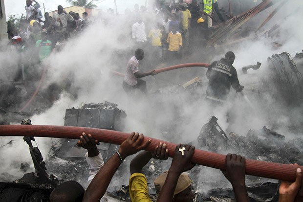 Nigerianos tentam apagar incêndio em local onde ocorreu acidente aéreo, na cidade de Lagos (Foto: Akintunde Akinleye/Reuters)