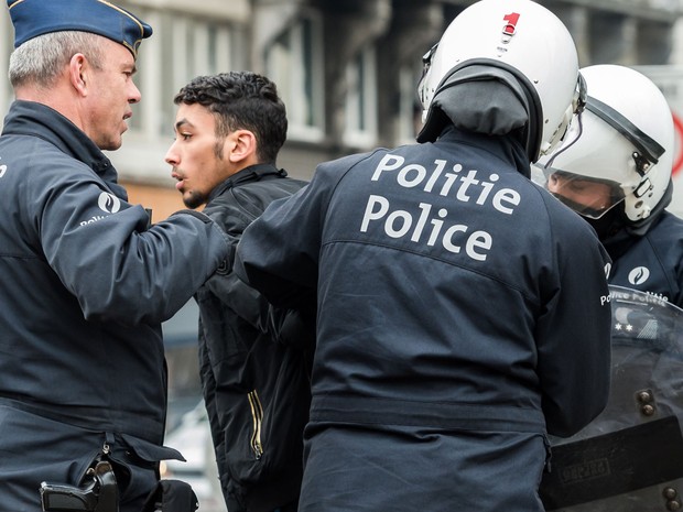 Policiais detém jovem durante uma manifestação no distrito de Molenbeek, em Bruxelas, na Bélgica, no sábado (2) (Foto: AP Photo/Geert Vanden Wijngaert)