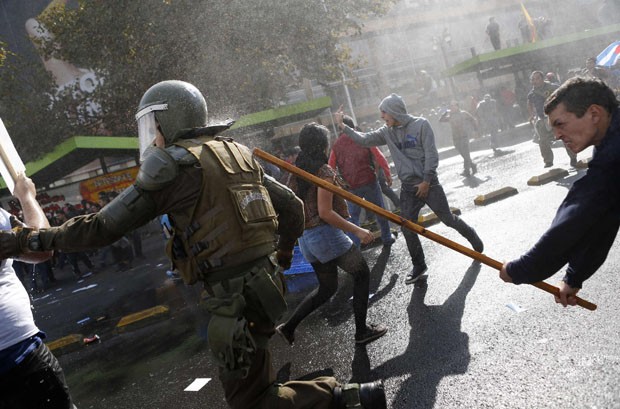 Homem acerta policial com um pedaço de pau (Foto: Ivan Alvarado/Reuters)