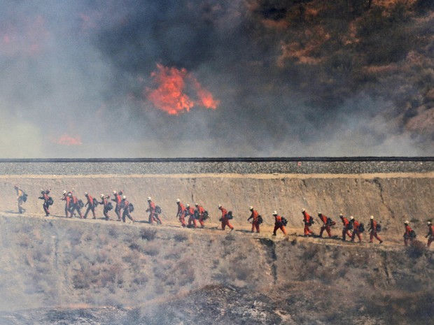 Equipe de bombeiros se aproxima de incêndio nesta sexta-feira, em Santa Clarita (Foto: Katharine Lotze/The Santa Clarita Valley/AP Photo)