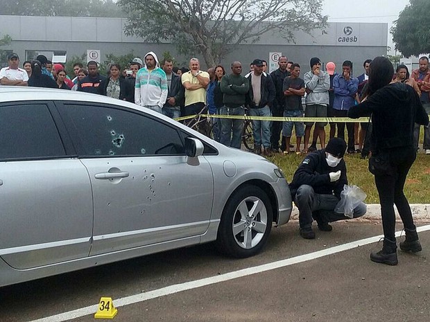 Perito recolhe cápsulas de munição junto a carro de acusado de tentatuva de homicídio morto pouco antes de julgamento no Fórum de Santa Maria, no Distrito Federal, na manhã desta quinta (28) (Foto: Fernando Caixeta/G1)