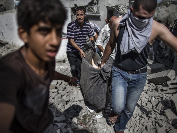  Palestinos tiram corpo de homem morto em sua casa em bombardeio; trégua de 12 horas começou na manhã deste sábado (Foto:  AFP Photo/Marco Longari)