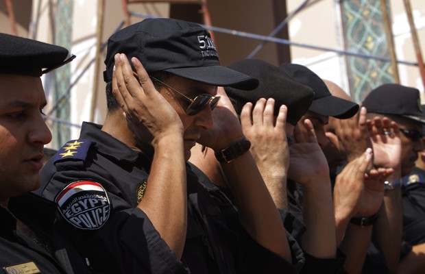 Policiais egípcios oram durante funeral de militares mortos em confronto com manifestantes (Foto: Amr Nabil/AP)