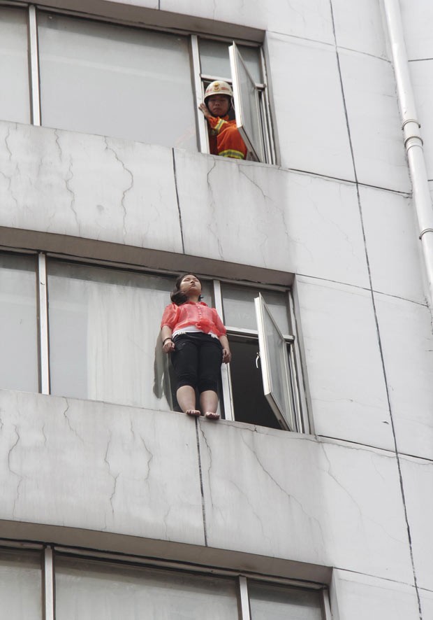 Mulher é flagrada ameaçando se jogar de prédio em Jiujiang, na China, nesta quarta-feira (14) (Foto: Reuters/Stringer)