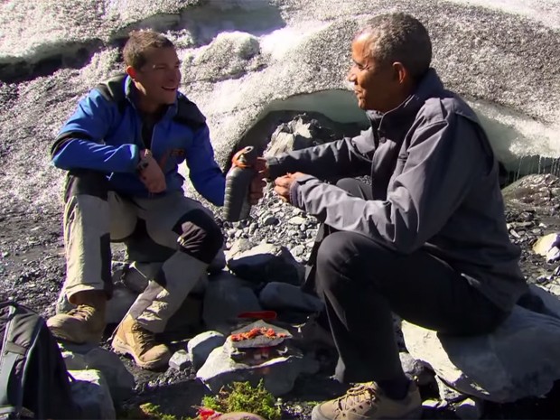 Bear Grylls e Barack Obama comem pedaços de salmão que foi devorado por um urso, em episódio de 'Running Wild With Bear Grylls' (Foto: Reprodução/Youtube/Running Wild With Bear Grylls)