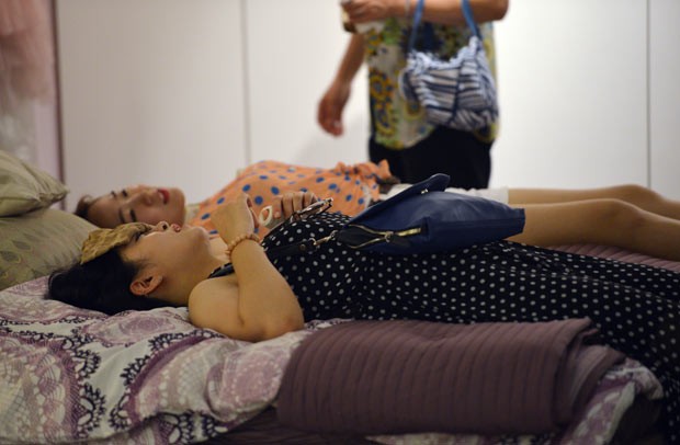 Mulheres aproveitam ar condicionado de loja de móveis nesta quarta-feira (31) em Xangai (Foto: Peter Parks/AFP)