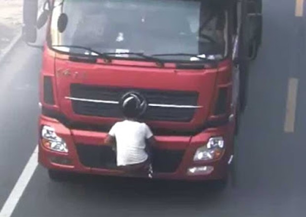 Motorista foi flagrado carregando amigo pendurado no para-choque dianteiro, com o objetivo de esconder a placa (Foto: Reprodução/YouTube/CCTV News)