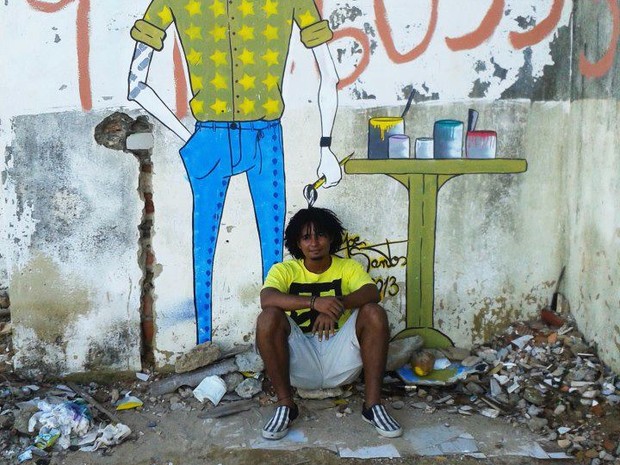 Joe Santos em frente a uma de suas pinturas, no bairro de Cruz das Almas (Foto: Divulgação/Facebook)