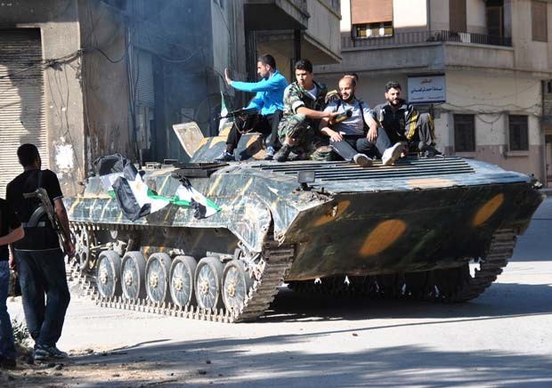 Soldados desertores e rebeldes descansam sobre tanque no distrito de Khaldiyeh, na prov&iacute;ncia de Homs, na regi&atilde;o central da S&iacute;ria, neste s&aacute;bado (12) (Foto: AP)