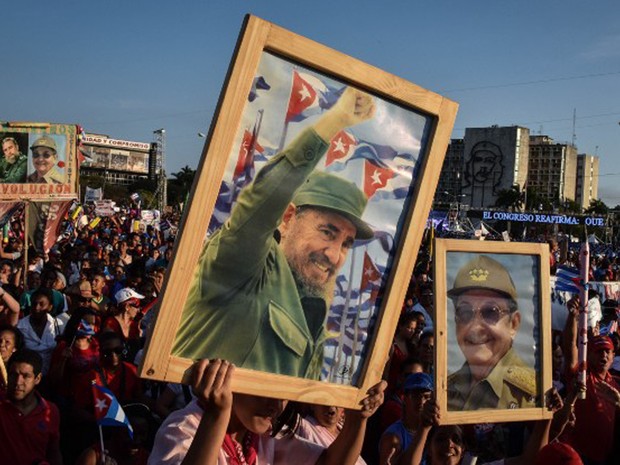 Cubanos mostram fotografias do ex-presidente Fidel Castro e do atual, Raúl Castro, na festa do 1º de maio (Foto: Adalberto Roque / AFP)