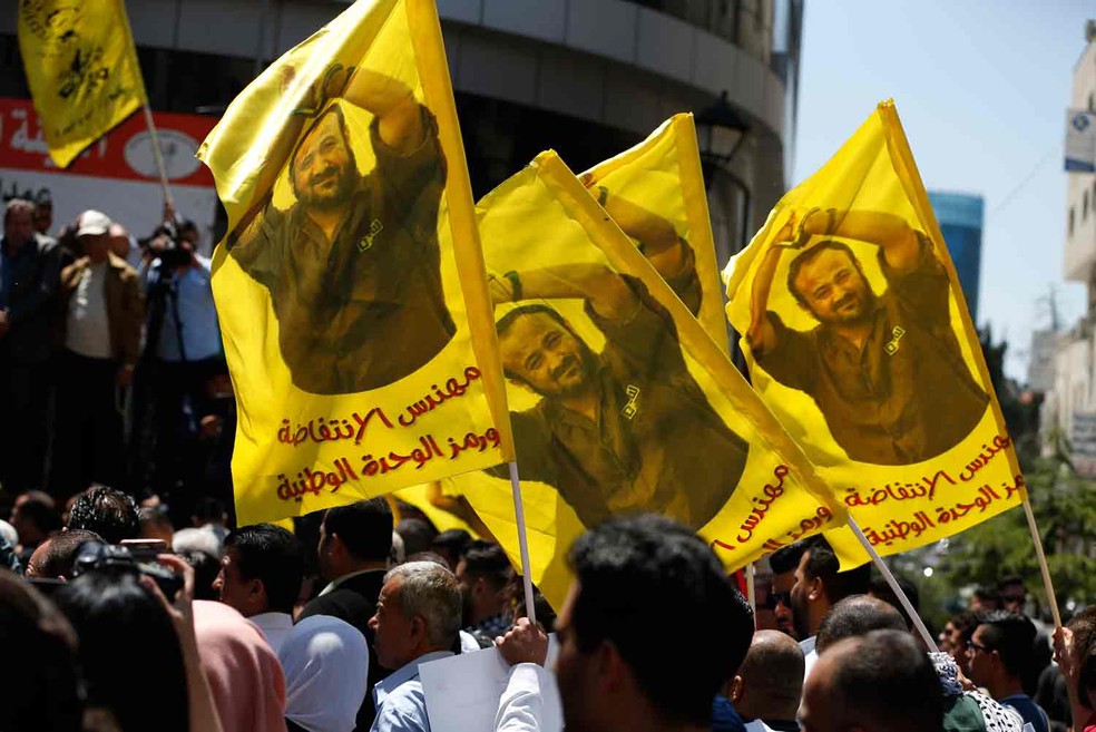 Manifestantes carregam bandeiras com a foto do palestino Marwan Barghouti, pisioneiro que convocou greve de fome  (Foto: Abbas Momani/AFP)