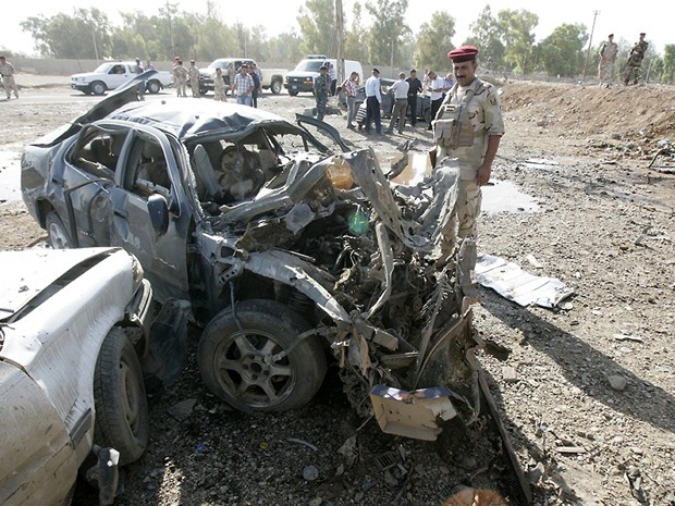 Soldado iraquiano inspeciona a explosão que veio de um carro, a 15 km da cidade de Kirkuk, neste domingo (9) (Foto: AFP)