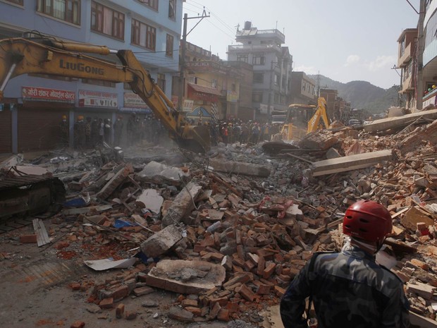 Escavadeiras removem os detroços de um prédio que desmoronou no terremoto desta terça-feira (12) em Catmandu, no Nepal (Foto: Niranjan Shrestha/AP)