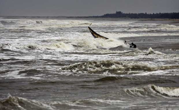 Pescadores indianos tentam equilibrar o barco e puxá-lo para fora da Baía de Bengala, na Índia, nesta sexta-feira (11) (Foto: Biswaranjan Rout/ AP)