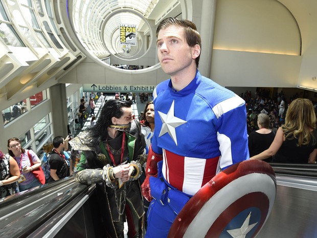 Um desatento visitante fantasiado de Capitão América sobe as escadas rolantes, à frente de Loki, o irmão de Thor, na feira Comic-Con 2014, em San Diego (EUA). (Foto: Denis Poroy/France Presse) Um desatento visitante fantasiado de Capitão América sobe as escadas rolantes, à frente de Loki, o irmão de Thor, na feira Comic-Con 2014, em San Diego (EUA). (Foto: Denis Poroy/France Presse)