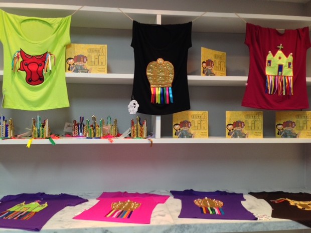 Além dos chepéus, há camisas e o livro infantil &#39;Um Vestido para Lia&#39; à venda na exposição (Foto: Michelle Farias/G1)