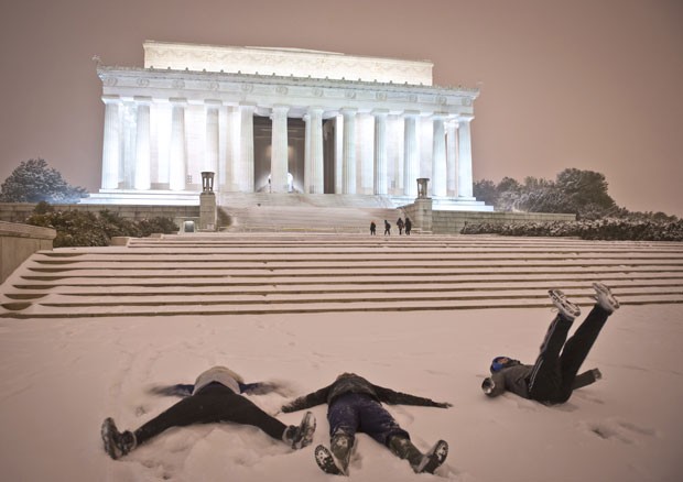 Pessoas se divertem fazendo 'anjinhos' na neve em frente ao Memorial de Lincoln, ponto turístico de Washington (Foto: Mladen Antonov/AFP)