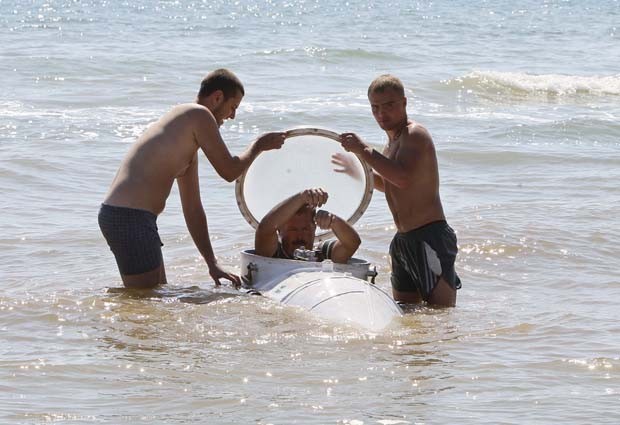 O inventor entra no submarino com a ajuda de dois assistentes (Foto: Gleb Garanich/Reuters)