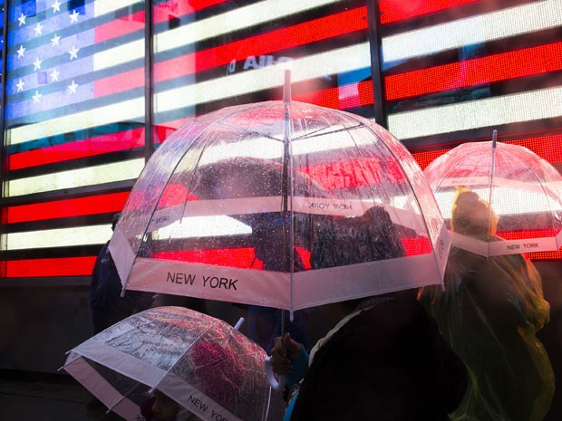 Pedestres se protegem da chuva na Times Square, em Nova York (Foto: AP)