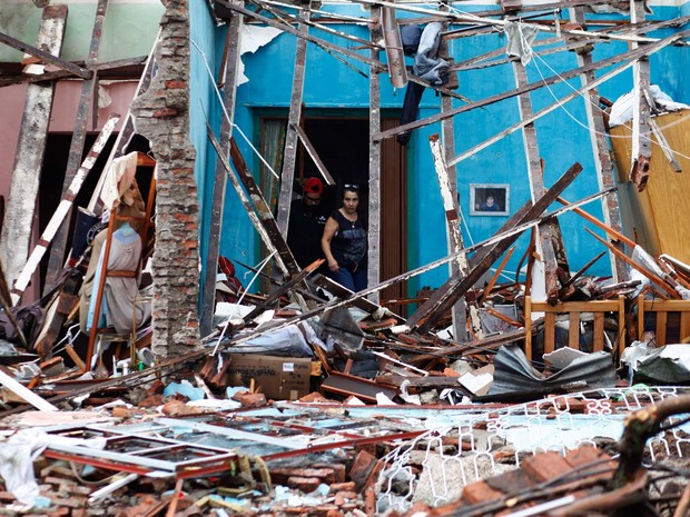 Mulher olha para destroços de casa atingida por temporal na cidade de Dolores, Uruguai (Foto: Nicolas Garcia / AFP)