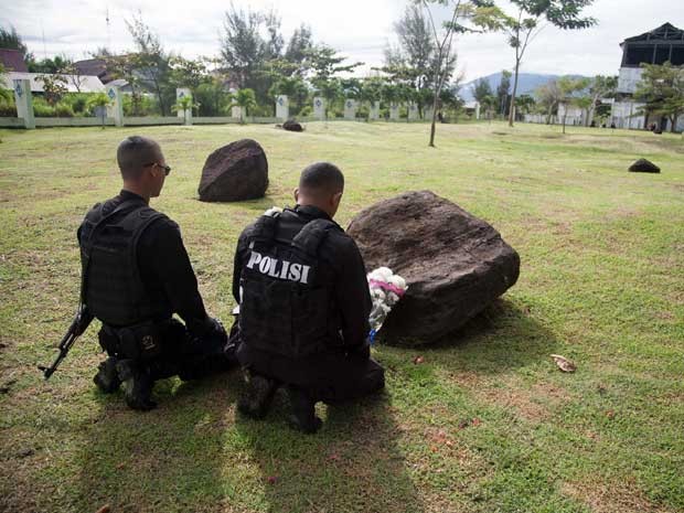 Policiais rezam por seus amigos e parentes mortos em uma vala comum para as vítimas do grande tsunami de 2004. (Foto: Chaideer Mahyuddin / AFP Photo) Policiais rezam por seus amigos e parentes mortos em uma vala comum para as vítimas do grande tsunami de 2004. (Foto: Chaideer Mahyuddin / AFP Photo)