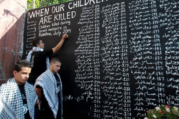 Jovem palestino anota nome de criança morta durante conflito entre forças israelenses e do Hamas (Foto: Musa Al Shaer/AFP)