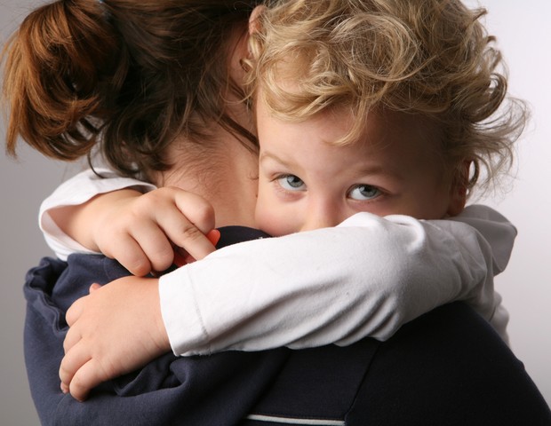 Criança triste no colo da mãe (Foto: Shutterstock)