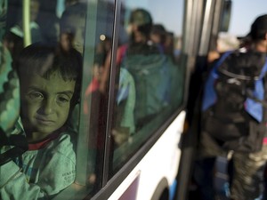 Criança imigrante é vista em janela de ônibus após chegar do navio de passageiros no porto de Piraeus, perto de Atenas (Foto: Stoyan Nenov/Reuters)