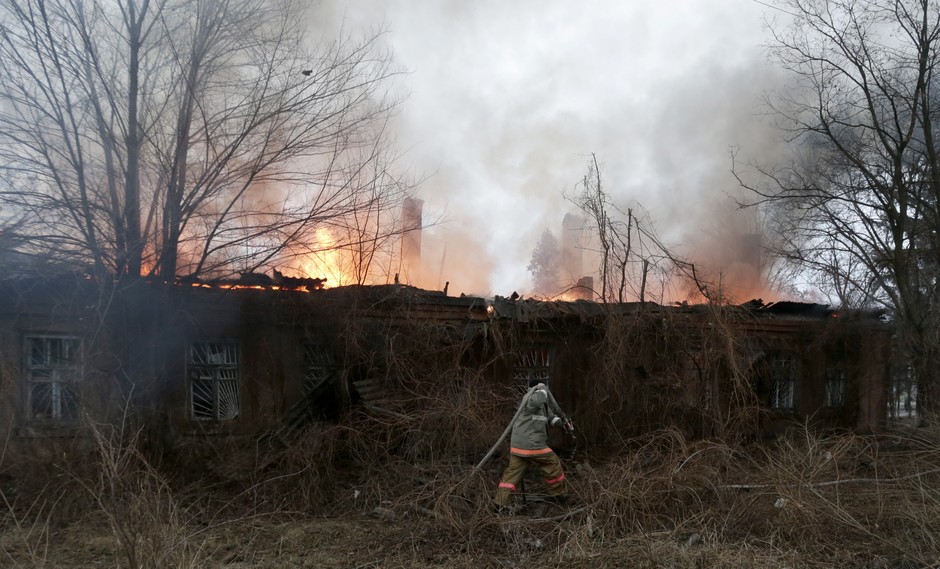 A firefighter carries a hose in an effort to extinguish a building on fire after shelling between Russian-backed separatists and Ukrainian government in residential area of the town of  Artemivsk, Ukraine, Saturday, Feb. 14, 2015. Despite a looming cease-