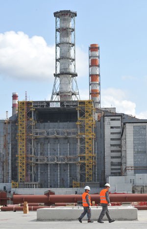 Trabalhadores caminham em frente à obra da nova estrutura de proteção em Chernobyl (Foto: Genya Savilov/AFP)