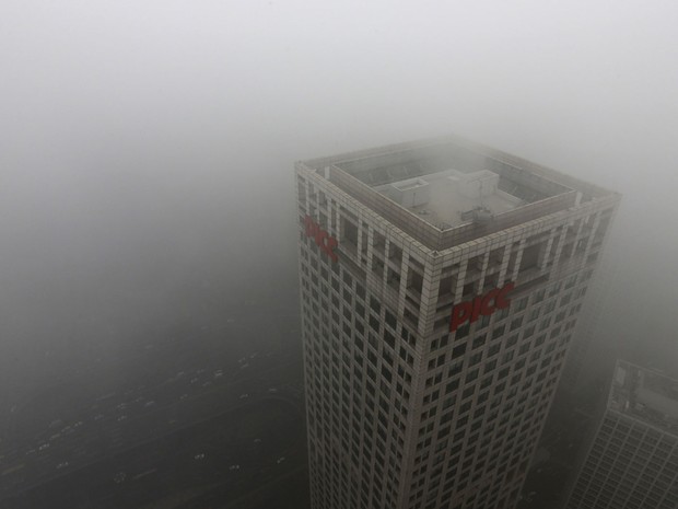 Parte de prédio é vista em meio à névoa de poluição que encobre Pequim. A capital chinesa advertiu que seus moradores devem permanecer em casa após o anúncio de medidas de emergência para combater uma pesada neblina de poluição. (Foto: Jason Lee/Reuters)