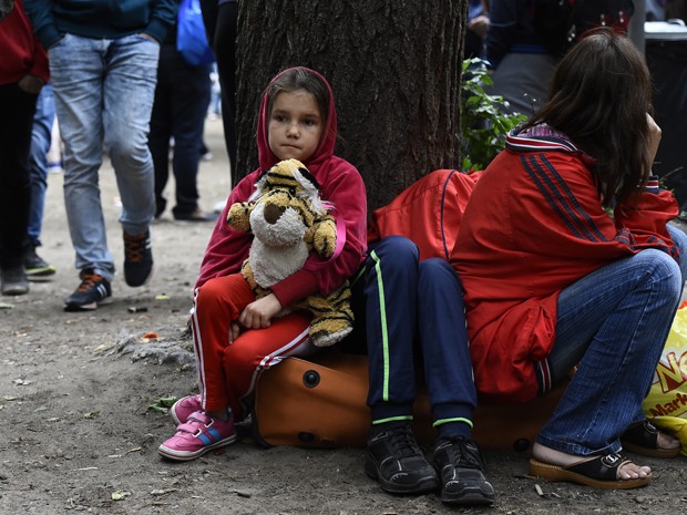 Criança imigrante aguarda do lado de fora da Secretaria de Estado de Saúde e Assuntos Sociais, em Berlim, na terça (25) (Foto: AFP Photo/Tobias Schwarz)